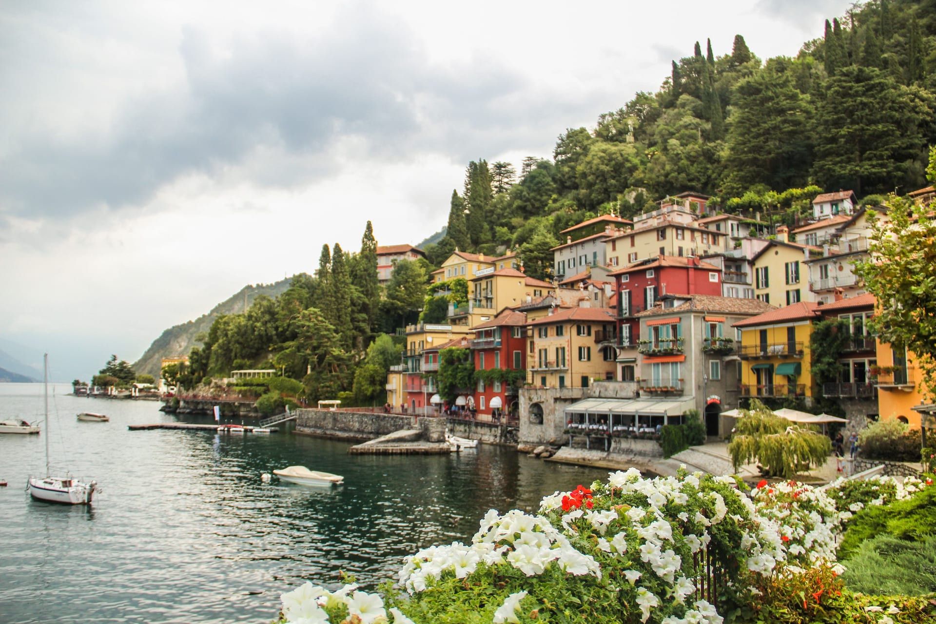 Il piccolo porto di Varenna sul Lago di Como, con le case colorate, le barche e i fiori in primo piano
