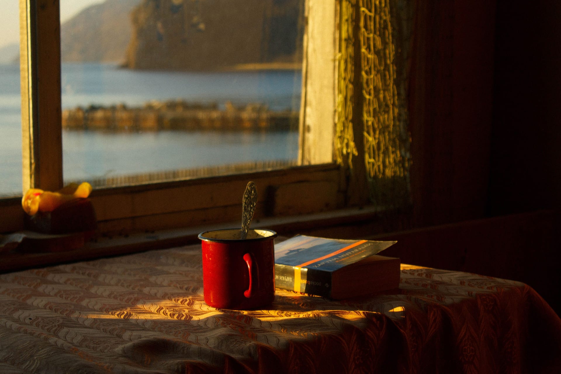 Une fenêtre donnant sur le lac, avec une tasse et un livre sur le rebord